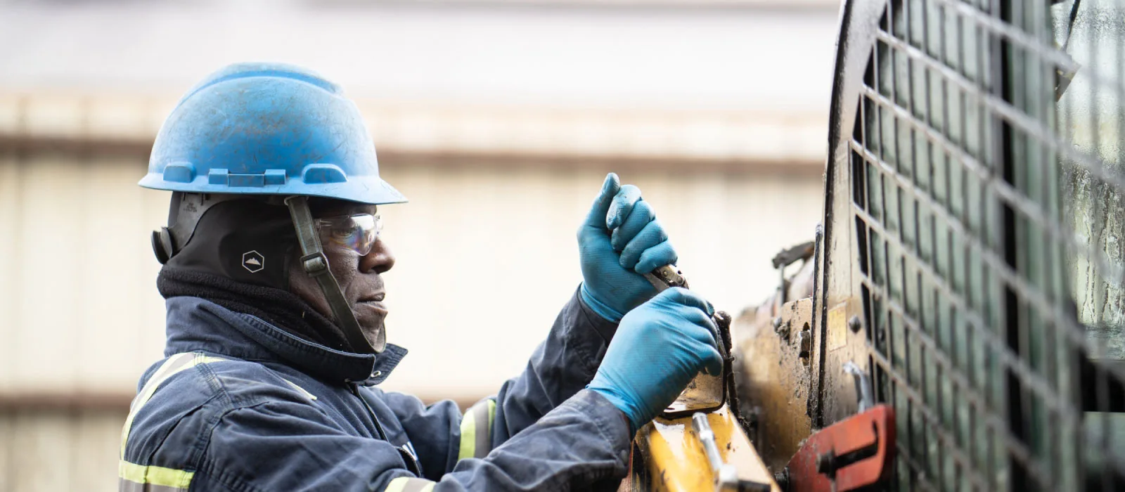 Bulk technician in PPE wrenching on heavy equipment in the field