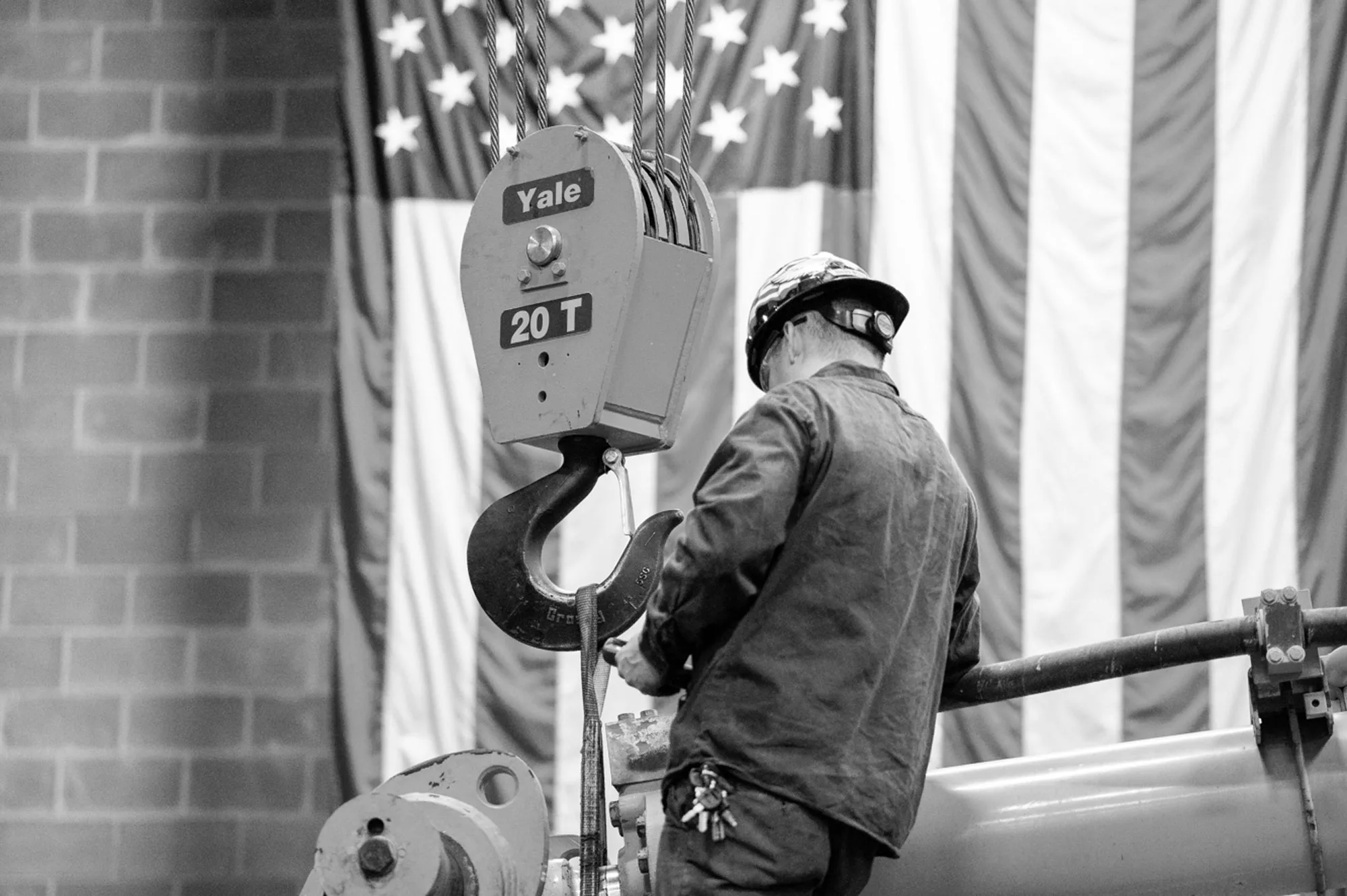 Bulk technician working under a 20 ton crane hook in front of an American flag