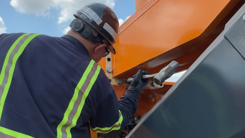mechanic hammering a KAMAG bult on a slag pot carrier