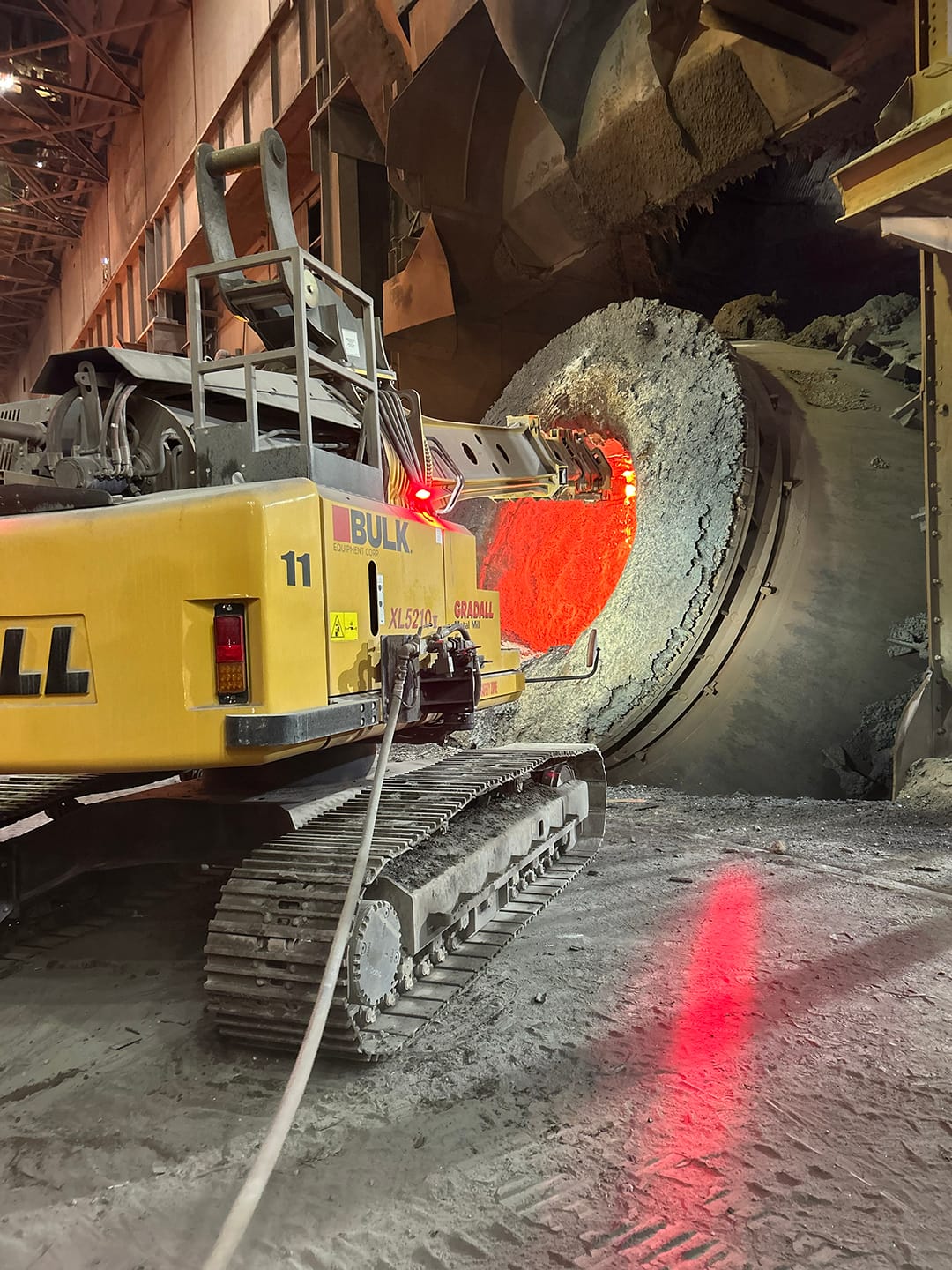 Bulk Gradall XL5210 V mill maintenance machine driving a pneumatic hammer into a hot vessel